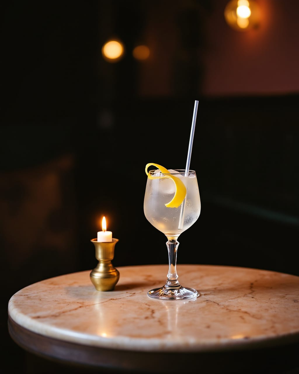 AI-genereret billede: En klar longdrink med citronskal ved et stearinlys på et rundt stenbord